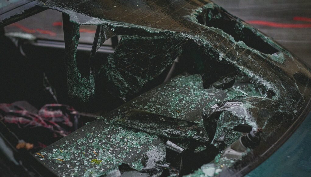 Detailed view of shattered car windshield after accident, emphasizing damage and broken glass.