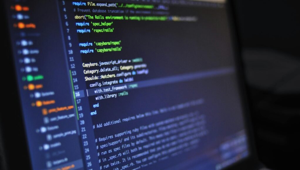 Close-up of a computer screen displaying programming code in a dark environment.