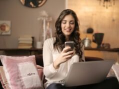 Online Muhasebe Programları: Yeni Nesil Finans Yönetimini Keşfedin A woman enjoying leisure time using her smartphone and laptop in a cozy living room.