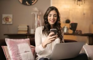Online Muhasebe Programları: Yeni Nesil Finans Yönetimini Keşfedin A woman enjoying leisure time using her smartphone and laptop in a cozy living room.